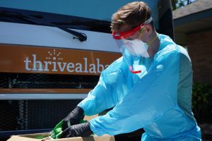 A health care worker goes through items in a box. He is wearing personal protective equipment.