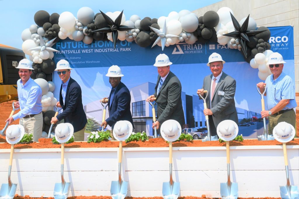 five adult men in hardhats holding shovels